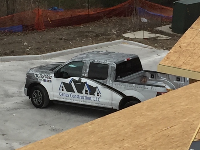 Genes Construction roofing truck on a new-construction job site beside roof decking in North Texas