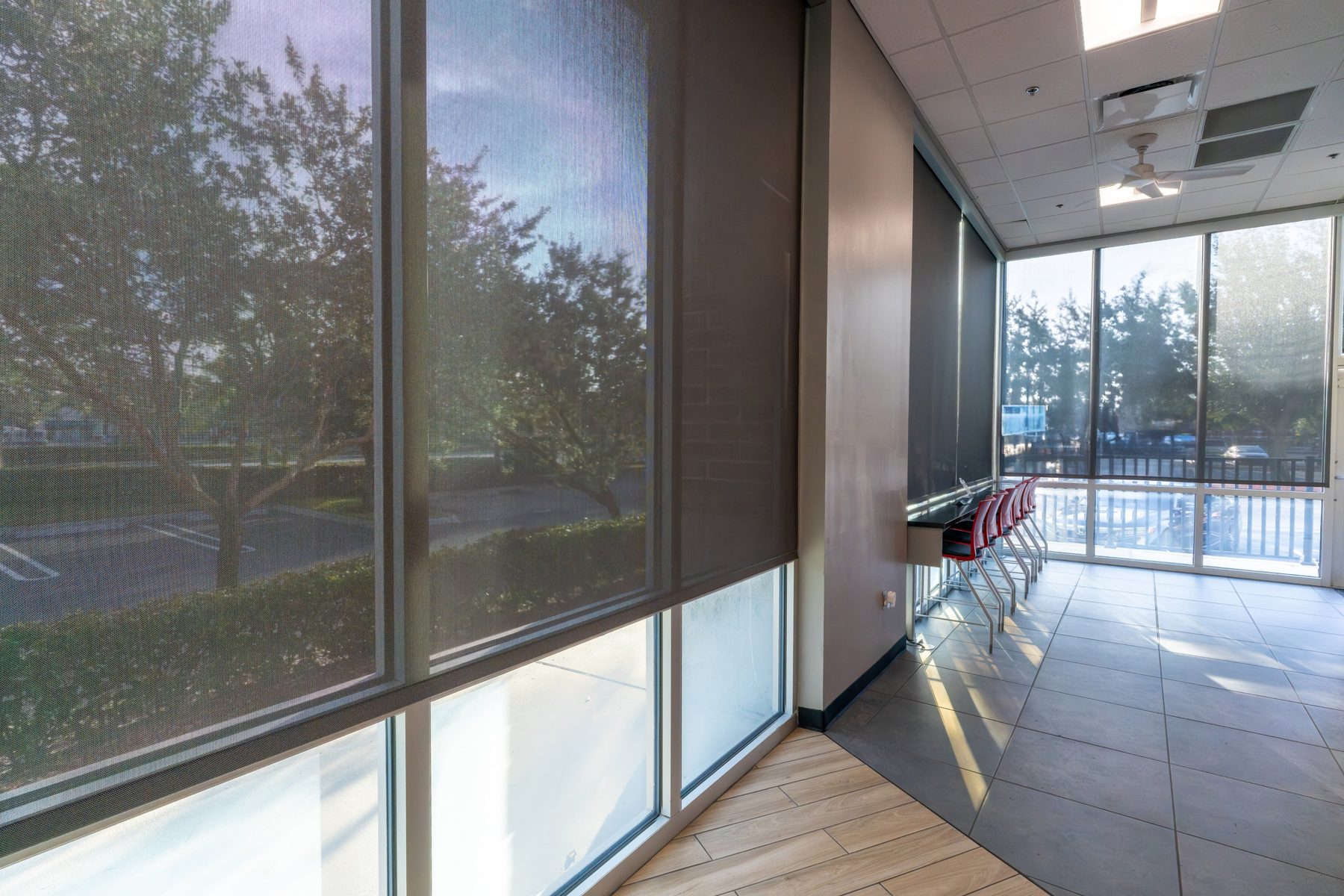 Interior solar roller shades on a window wall, half lowered to cut glare in a Frisco office or Prosper home