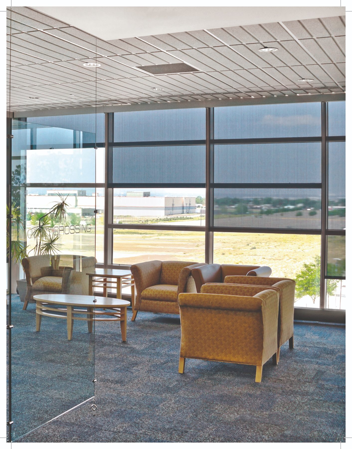 Interior solar shades on floor-to-ceiling glass in a lobby, specified for commercial window walls in Frisco and along the north Metroplex