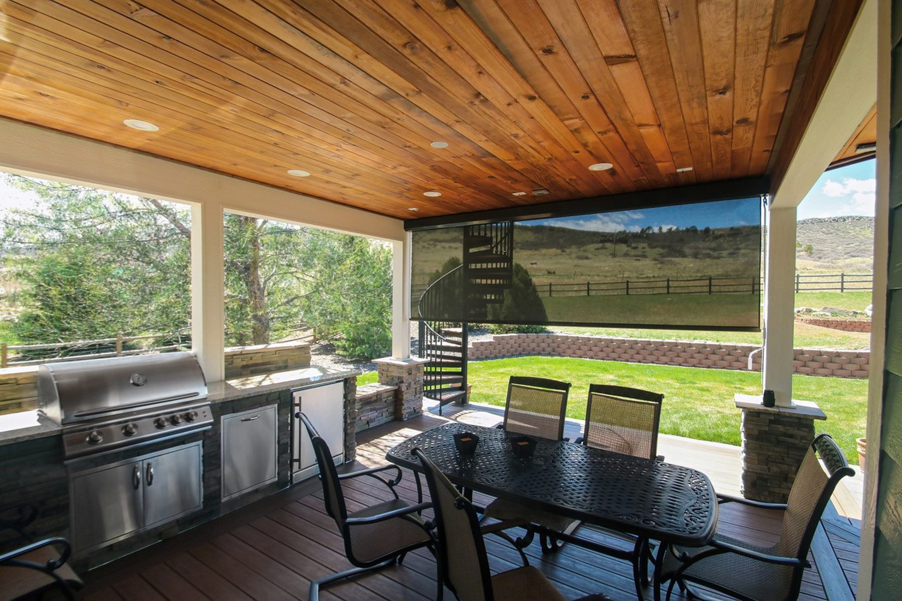 Outdoor kitchen and dining patio with a drop roller shade in a North Texas backyard, the kind of shade Genes Construction installs in Prosper and Celina